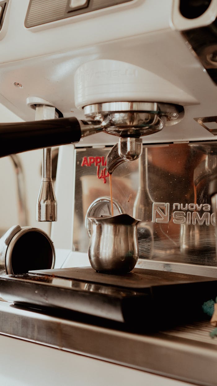 Close-up view of an espresso machine brewing coffee into a metal pitcher, showcasing modern coffee technology.